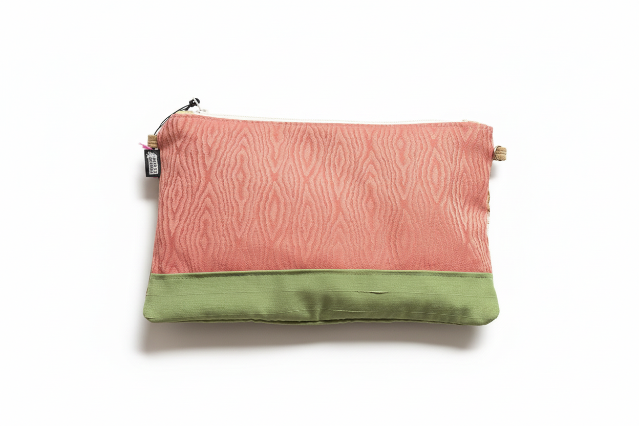 Coral pink and sage green two-tone clutch on white background