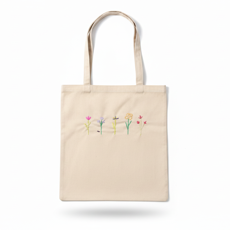 Cream beige canvas tote bag with embroidered wildflowers on white background
