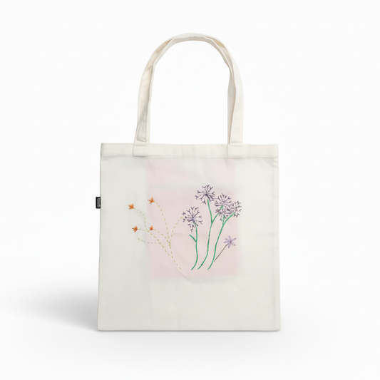 White tote bag with embroidered wildflowers on white background